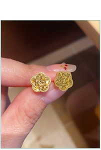 Nahaufnahme goldener Blumenohrstecker mit einer strukturierten, funkelnden Metalloberfläche