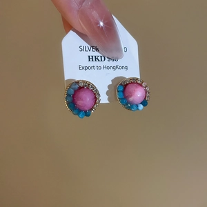 Detail of 925 silver stud earrings with pink center stone and blue bead halo