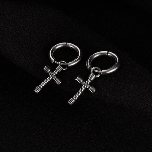 Detailed macro view of vintage cross pendant earrings with textured stainless steel surface