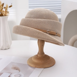 Élégant chapeau cloche en paille kaki avec sangle en cuir sur un support en bois épuré
