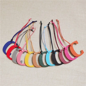 Multiple colorful leather letter C bag charms with matching straps on a beige background