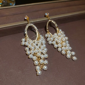 Macro shot of gold tassel pearl earrings with zircon inlay on brown leather stand