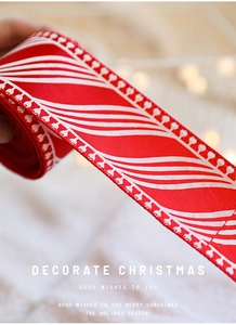 Close-up of red Christmas ribbon with white wave prints and festive bokeh lights