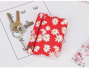 Macro detail of red canvas mini coin purse with daisy print and metal key ring chain