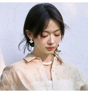 Detail view of ginkgo leaf pearl earrings worn by a model in natural light with soft shadows