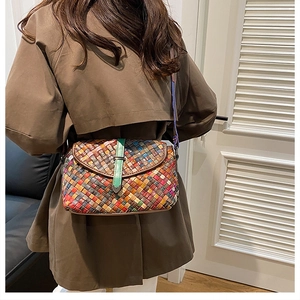 Détail d'un sac à bandoulière tressé coloré montrant des bandes de cuir et une boucle en métal