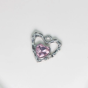 Close-up of hammered silver heart pendant with faceted pink gemstone and small crystal