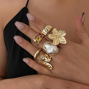 Close-up of gold ring set with pearls and colorful gemstones on female fingers