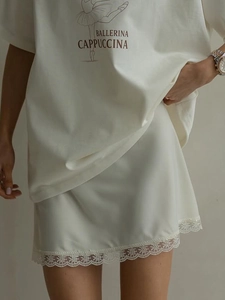 Detailed close-up of white satin skirt featuring intricate lace trim and floral embroidery