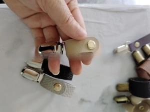 Detailaufnahme von bunten Leder-Hutclips mit Metallschnallen in verschiedenen Naturtönen