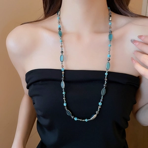 Détail d'un collier de perles turquoise et cristaux bleus sur un mannequin