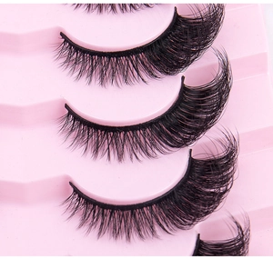 Detailed macro view of dense black cat-eye false eyelashes in pink plastic tray