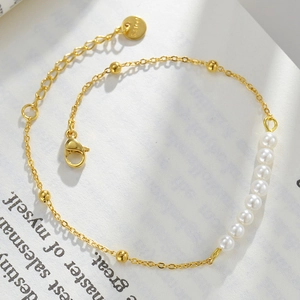 14k gold plated stainless steel bracelet with white pearls and gold beads on a book page
