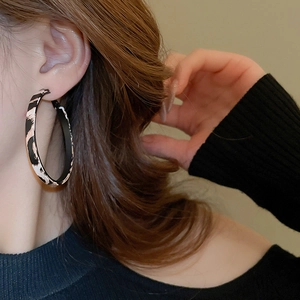 Close-up of leopard print hoop earrings worn by a model showcasing high fashion style