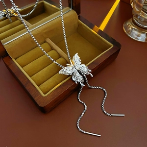 Detailed view of silver butterfly pendant necklace with intricate wing textures on wood
