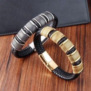 Close-up of braided leather bracelets with textured metal rings on wooden surface