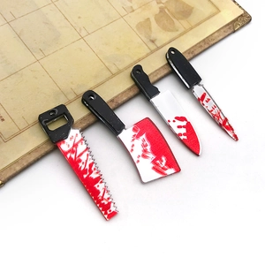 Macro view of four acrylic Halloween weapon charms with red blood splatters on white surface