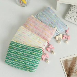 Set of four woven tweed coin purses in pastel colors with pearl bow charms on a desk
