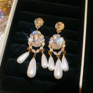 Detailed close-up of vintage gold teardrop pearl earrings with sparkling crystals