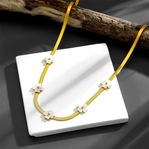 Detailed view of gold snake chain necklace with five white floral charms on stone base