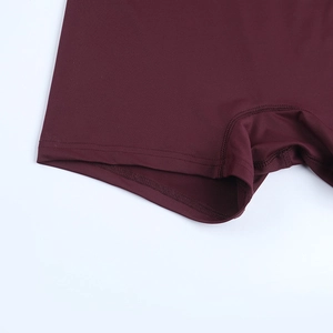 Macro shot of high-density double stitching on burgundy stretch yoga shorts hem