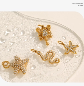 Macro shot of 18K gold-plated starfish, scorpion and snake charms with sparkling zircon