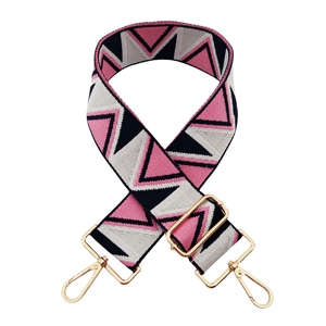 Detail of wide jacquard bag strap with pink and black triangle pattern and gold buckle