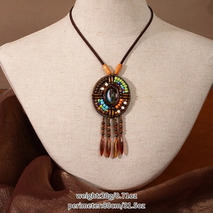 Detail of bohemian style long necklace with vintage ethnic pendant and tassel charms