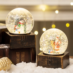 Lighted Christmas snow globe with snowman and Santa scenes on dark wood base