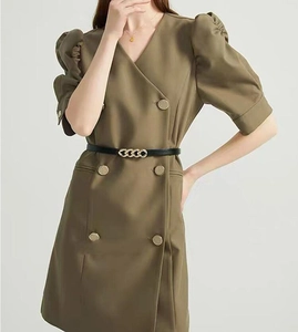 Detail of a green double-breasted dress featuring a black belt with a gold chain buckle