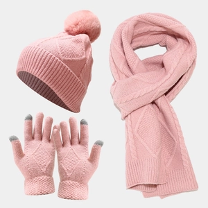 Close-up of pink knitted hat with pompom, long scarf and touchscreen gloves set