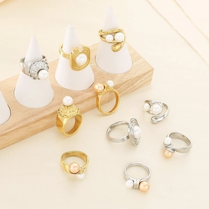 Close-up of gold and silver textured rings with pearl inlays on a wooden display stand