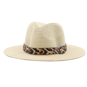 Detail of leopard print ribbon and gold metal buckle on a wide brim straw hat