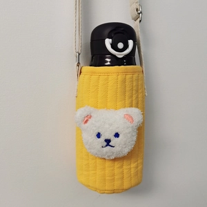 Close-up of yellow quilted fabric cup holder with a white plush bear head and adjustable strap