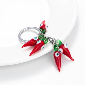 Red chili pepper keychain with evil eye charms on white ceramic plate for car keys