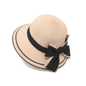 Close-up of beige straw sun hat with black ribbon and elegant large bow decoration