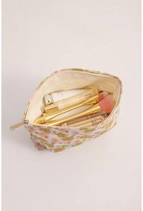 Macro detail of spacious floral makeup bag interior holding brushes and cosmetics