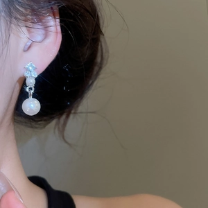Detail of elegant diamond and pearl earrings shown on model for a sophisticated look