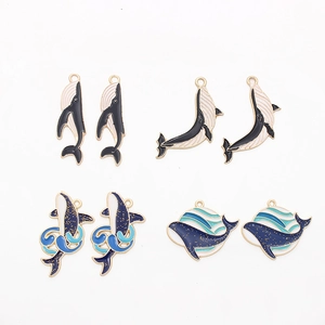 Detailed view of whale-themed enamel charms with gold trim and ocean wave patterns