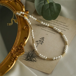 Elegant adjustable pearl and gold bead necklace on vintage book and silk background