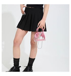 Détail d'un nœud rose et sac à bandoulière transparent en PVC avec chaîne en argent