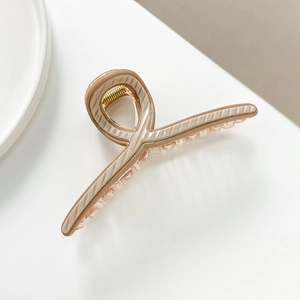 Macro shot of large nude hair claw clip with wave texture on a clean white background