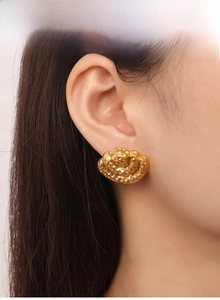 Detail of hammered gold fan earrings on model showing textured vintage finish