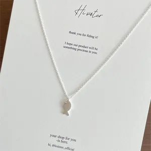 Detailed view of a 925 silver fish pendant necklace on a textured display card