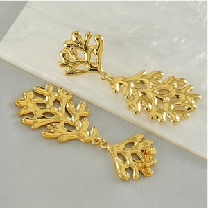 Detail of 18K gold-plated stainless steel leaf drop earrings on marble background