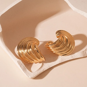 Detailed view of gold spiral striped geometric stud earrings on a textured stone display