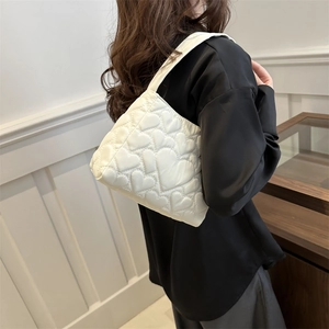 Sac à bandoulière blanc matelassé avec cœurs porté par un mannequin au style élégant