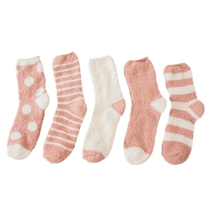 Five pairs of pink coral fleece socks with polka dots and stripes in a neat flat lay