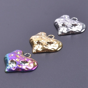 Macro detail of textured heart pendants with gems in gold, silver, and rainbow plating