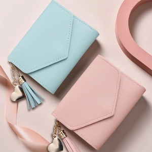 Detail of light blue and pink faux leather wallets with heart pendants and tassels